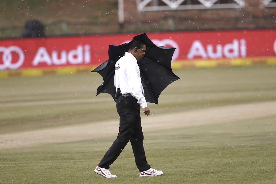 Umpire Shaun George takes shelter from rain