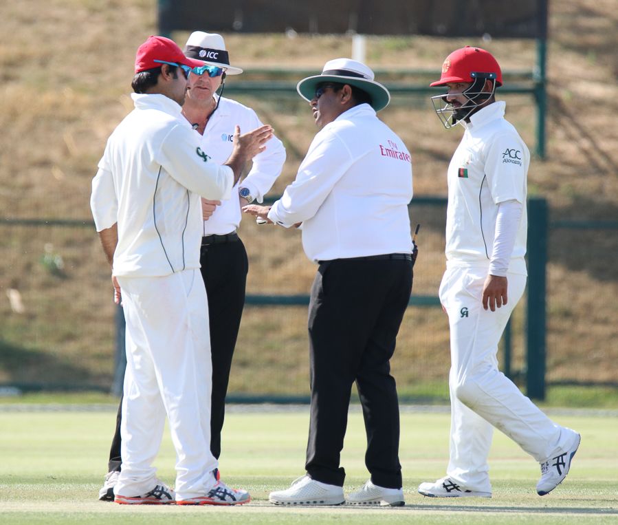 Umpire Ahsan Raza has a word with Afghanistan captain Asghar Stanikzai about his team's behavior
