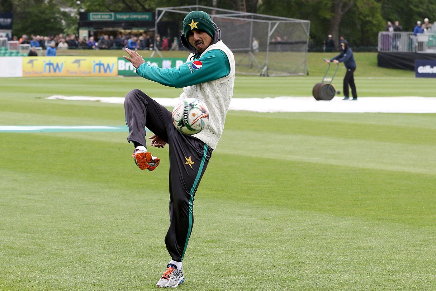 Saad Ali kicks a football around with his team-mates during a rain delay