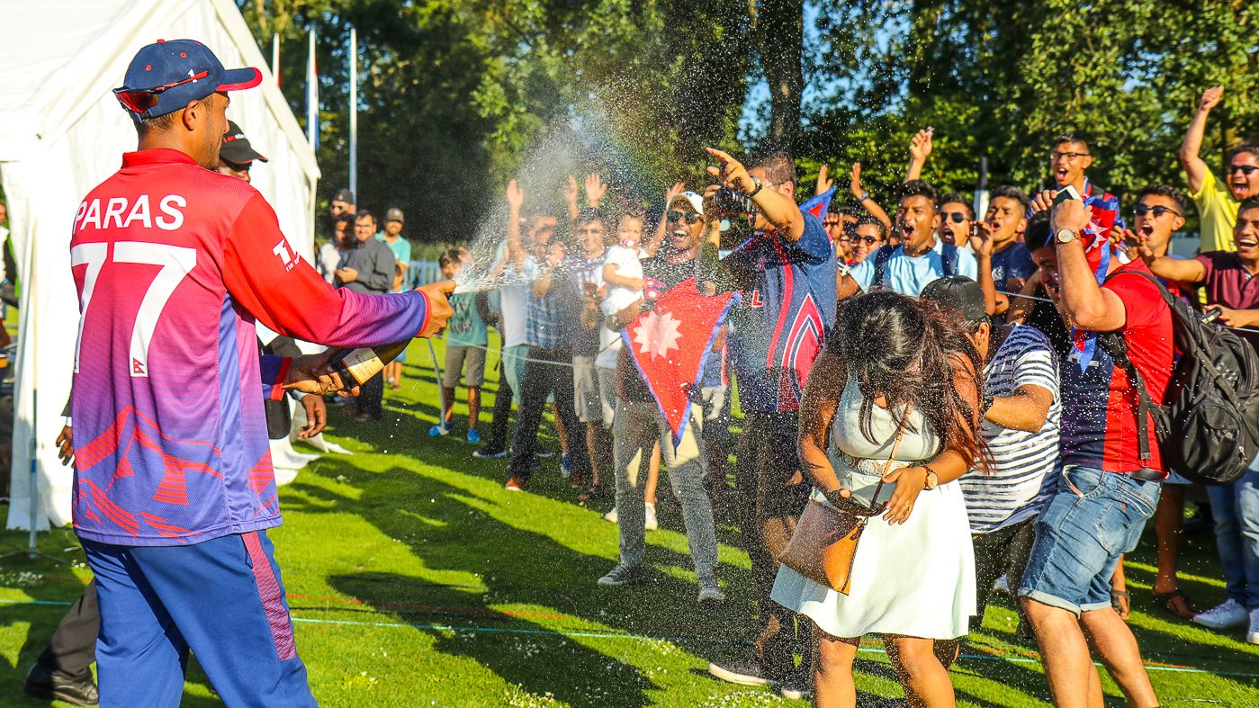 Paras Khadka gives the traveling Nepal fans a champagne shower to celebrate a famous win