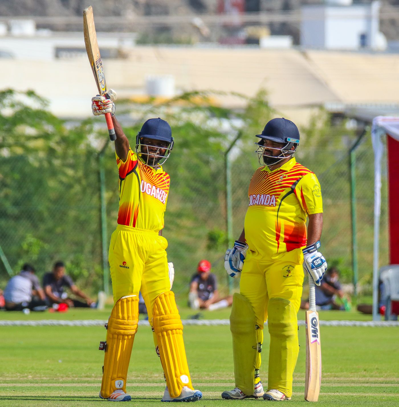Arnold Otwani grins and raises his bat high after raising a sharp half-century