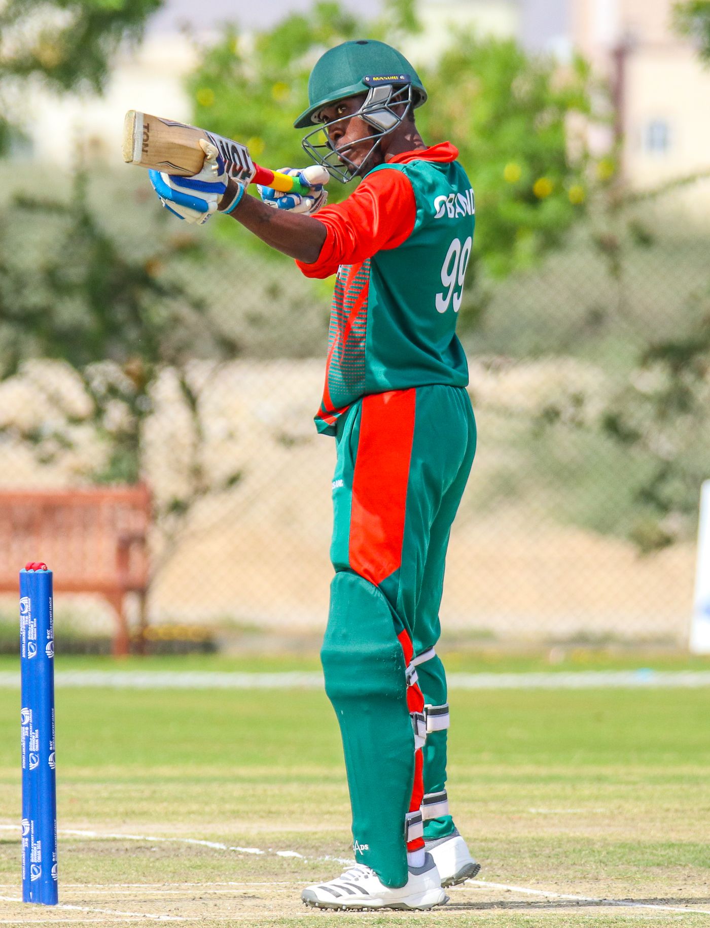 Alex Obanda turns his bat into a mock sniper rifle to celebrate a half-century