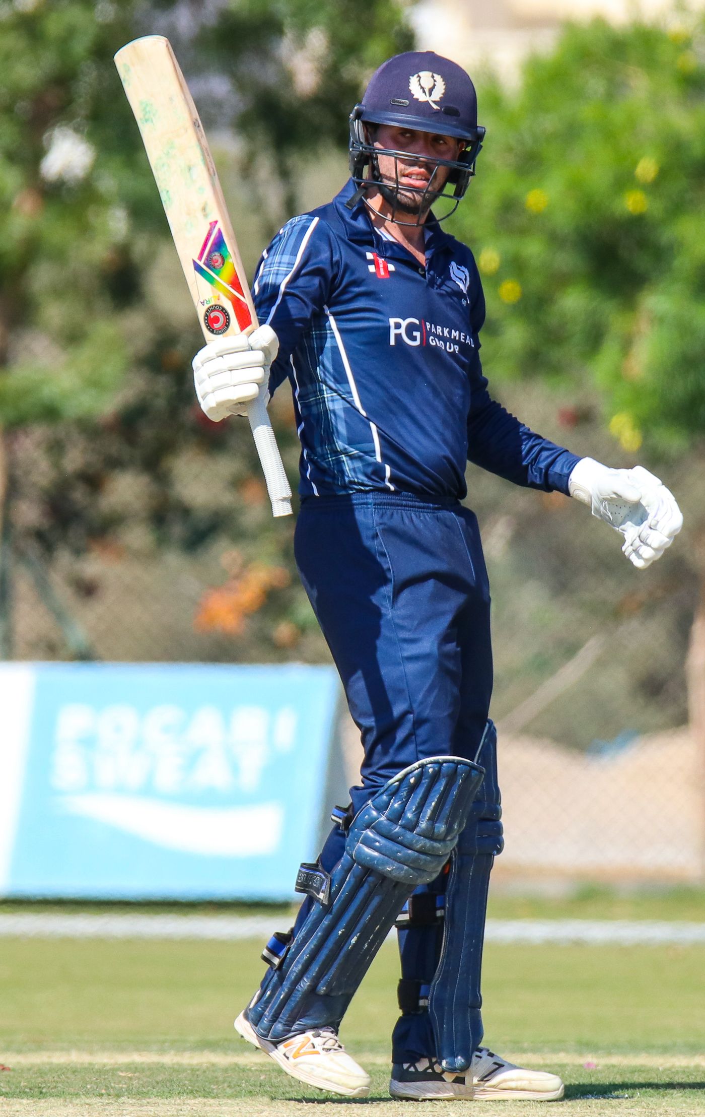 Calum MacLeod raises his bat toward the Scotland dressing room after reaching his fifty
