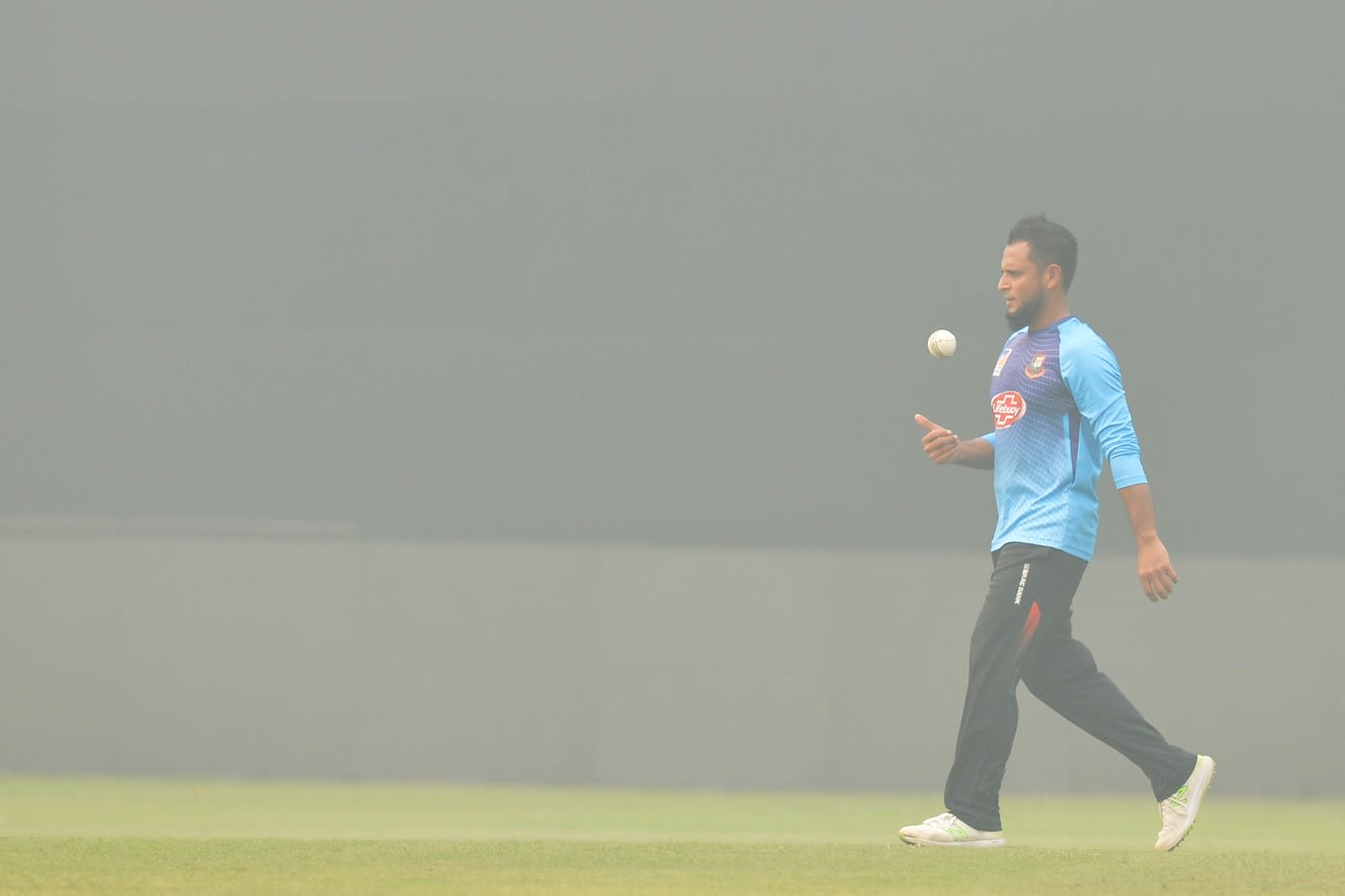 Arafat Sunny gears up to bowl at a practice session on a smoggy day