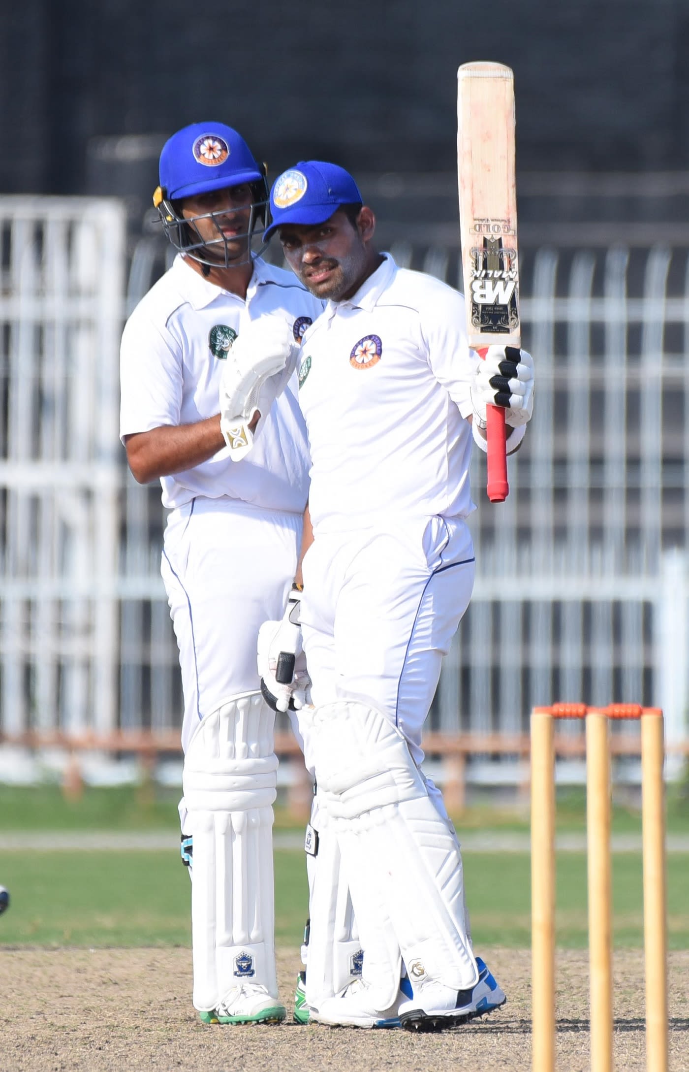 Umar Akmal raises his bat after reaching his fifty