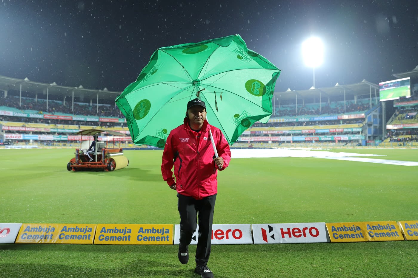 Umpire Virender Sharma jogs off the park as rain delays play