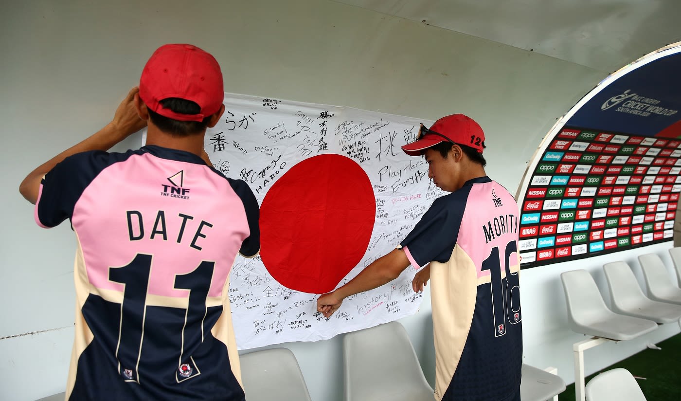 Neel Date and Masato Morita hang up a national flag with personal messages in the dugout