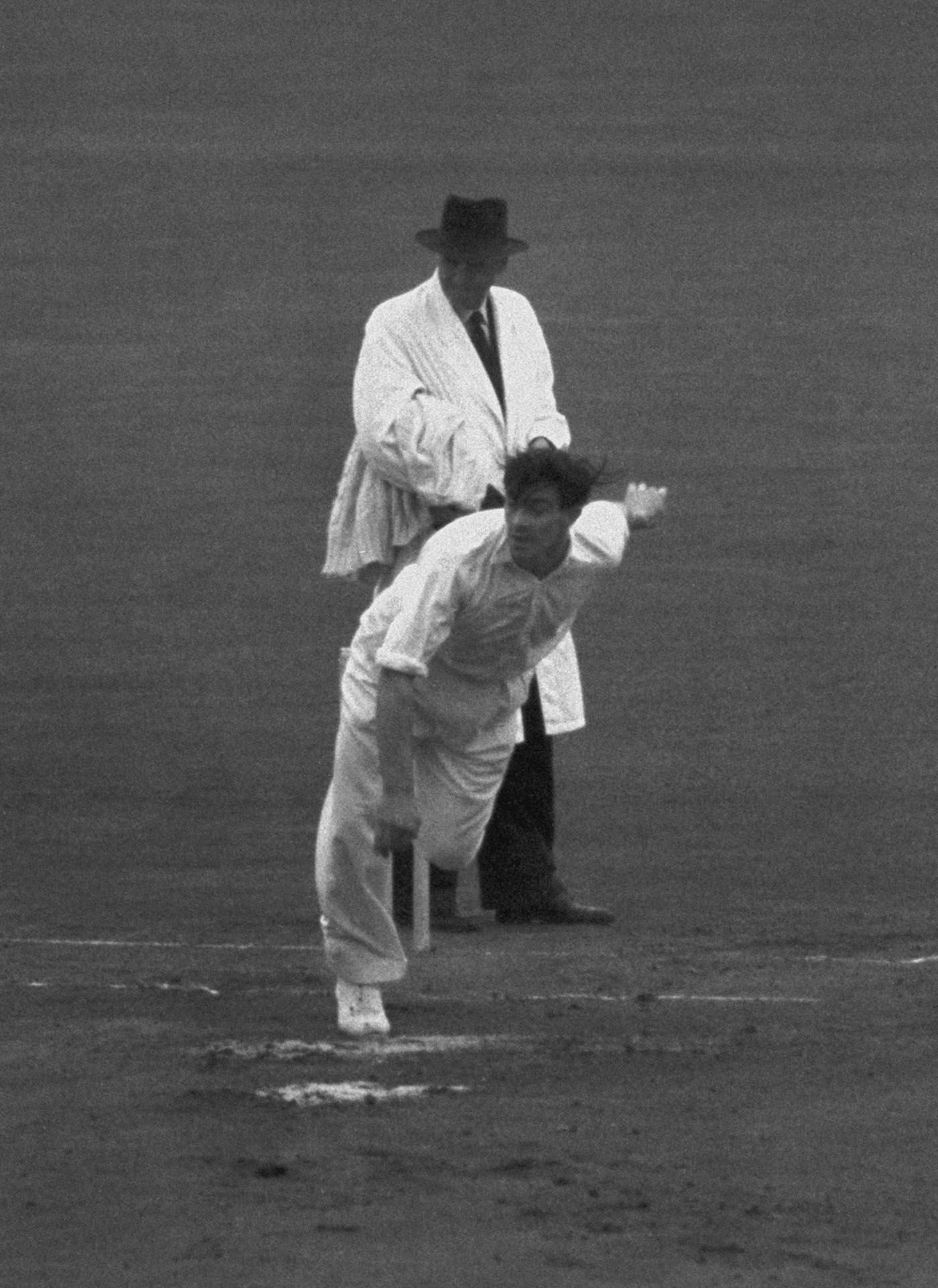 Umpire Frank Chester looks on as Fred Trueman bowls