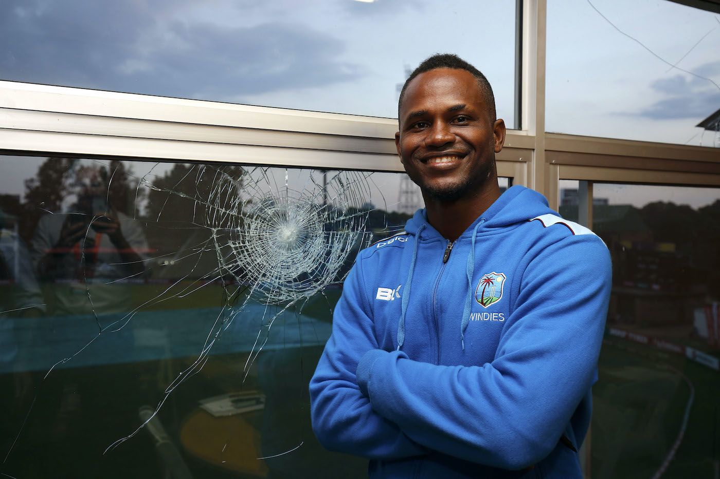 Marlon Samuels poses by the window he broke