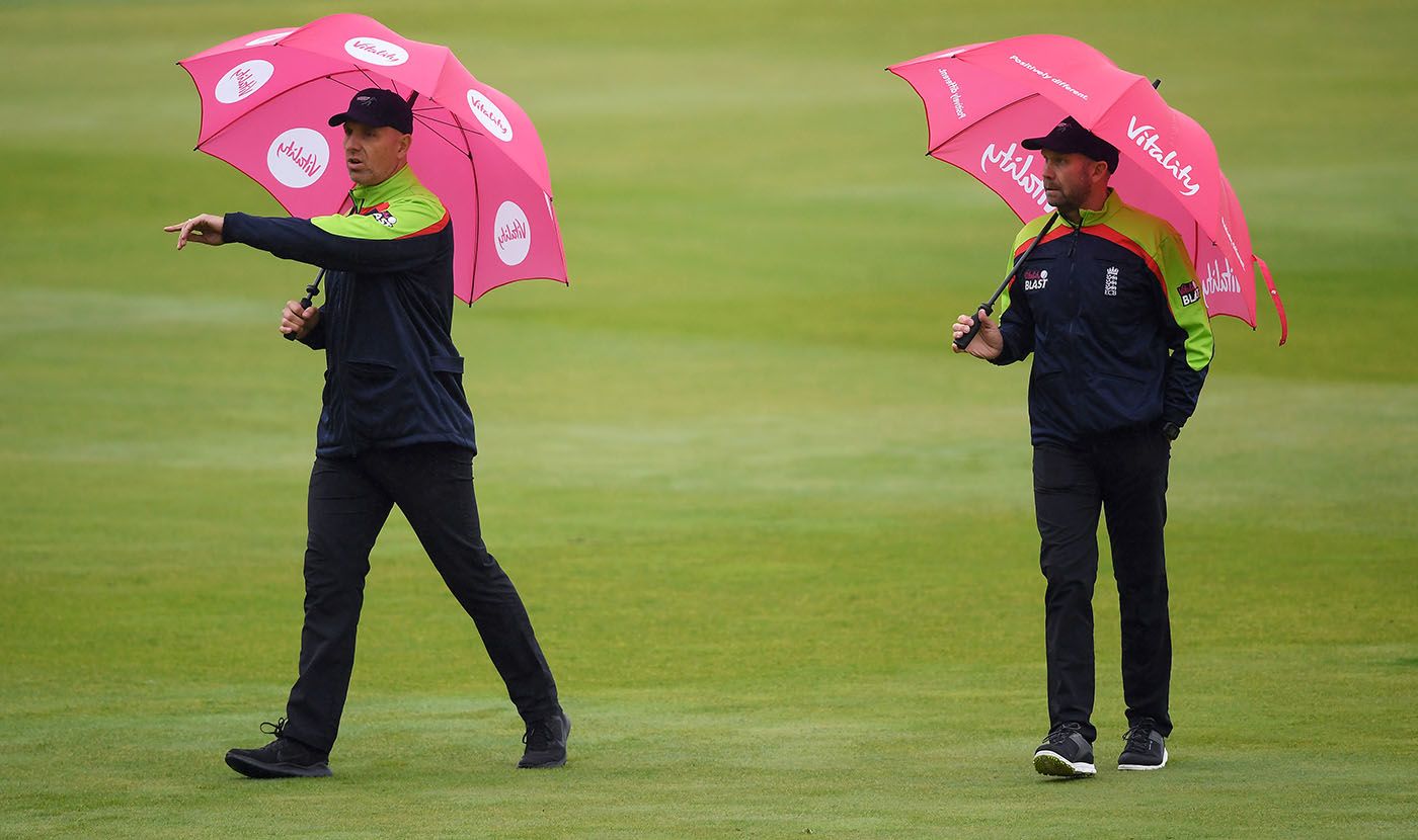 Umpires Alex Wharf and Mike Burns carry out an inspection