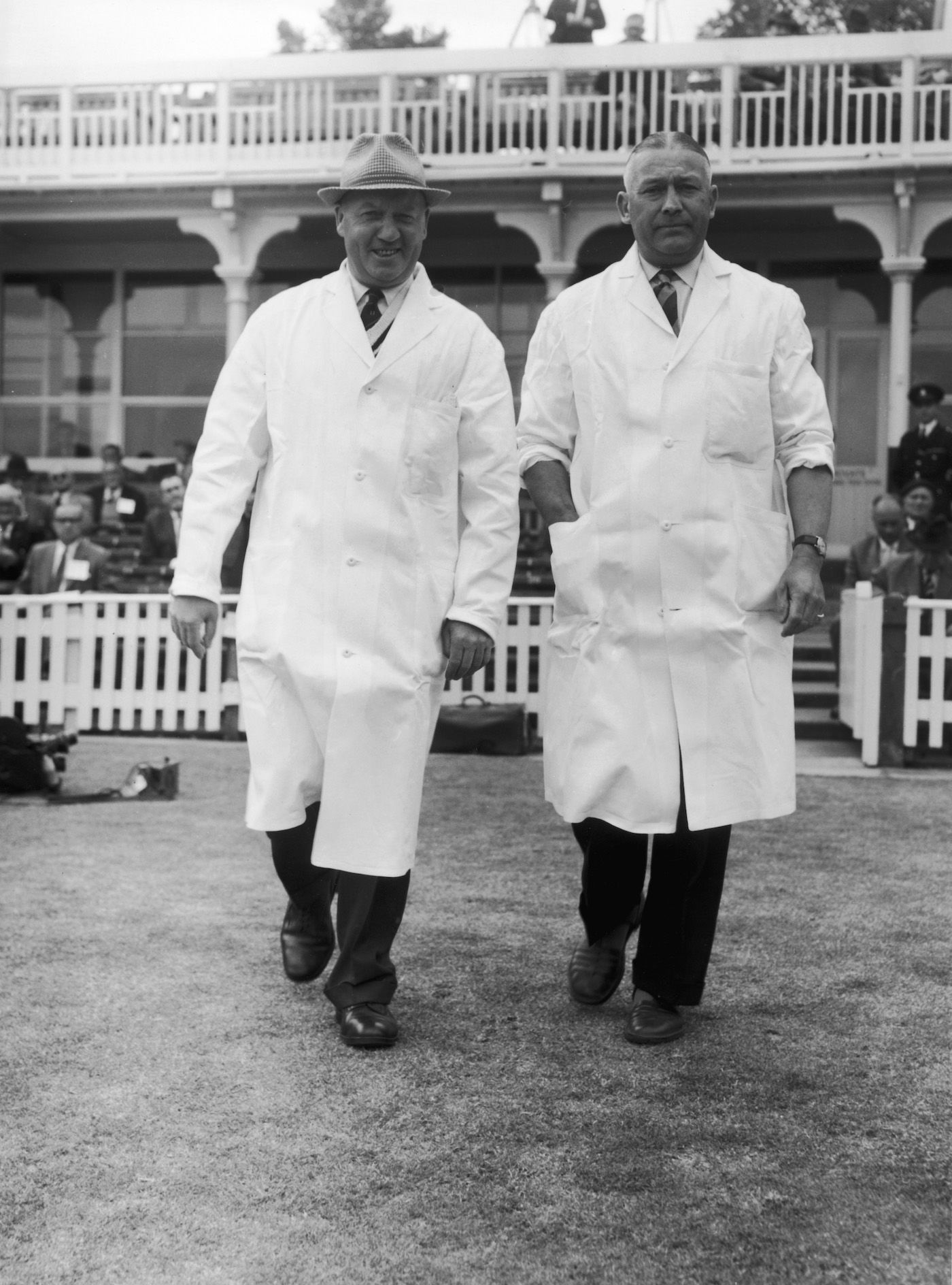 Umpires Frank Lee (left) and Syd Buller walk out onto the pitch
