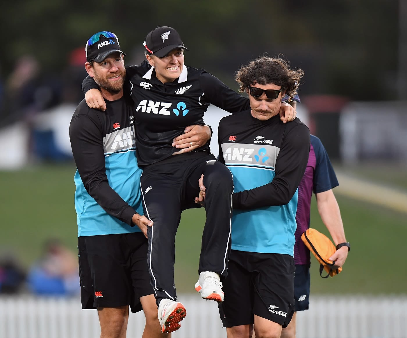 New Zealand bowling coach Jacob Oram (L) helps Lea Tahuhu off the field after she sustained a hamstring injury late in the game