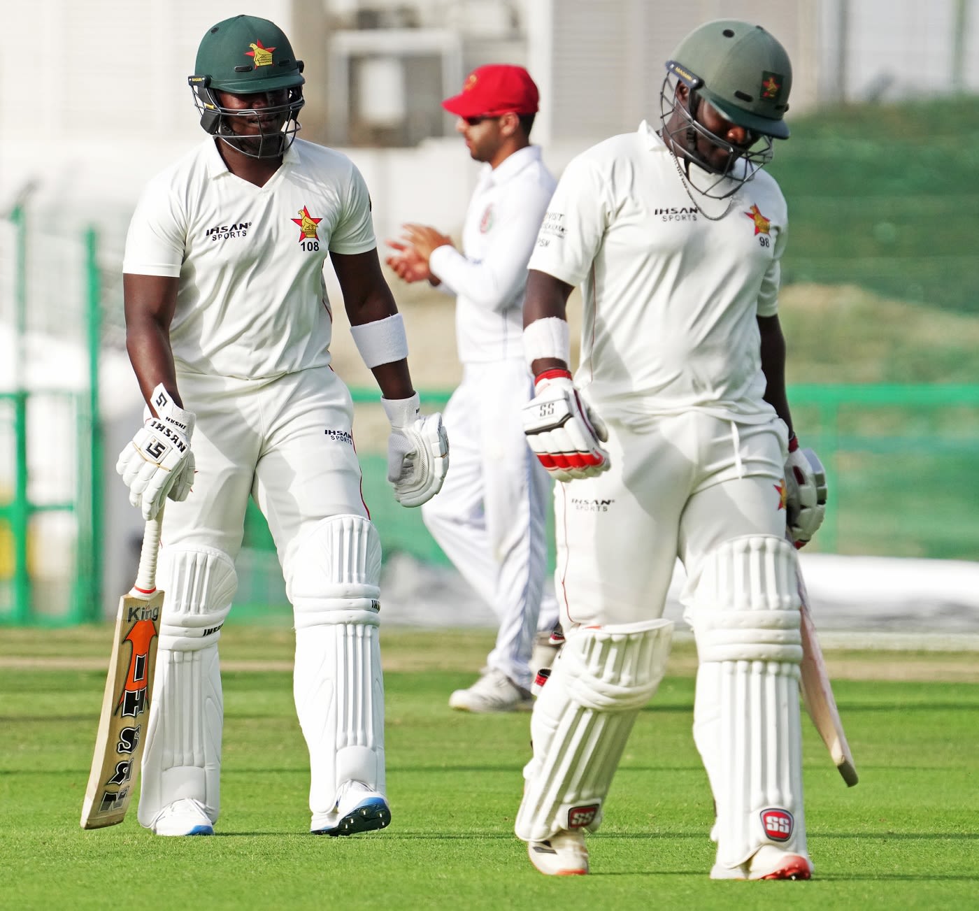 Prince Masvaure and Kevin kasuza walk off after the third day's play