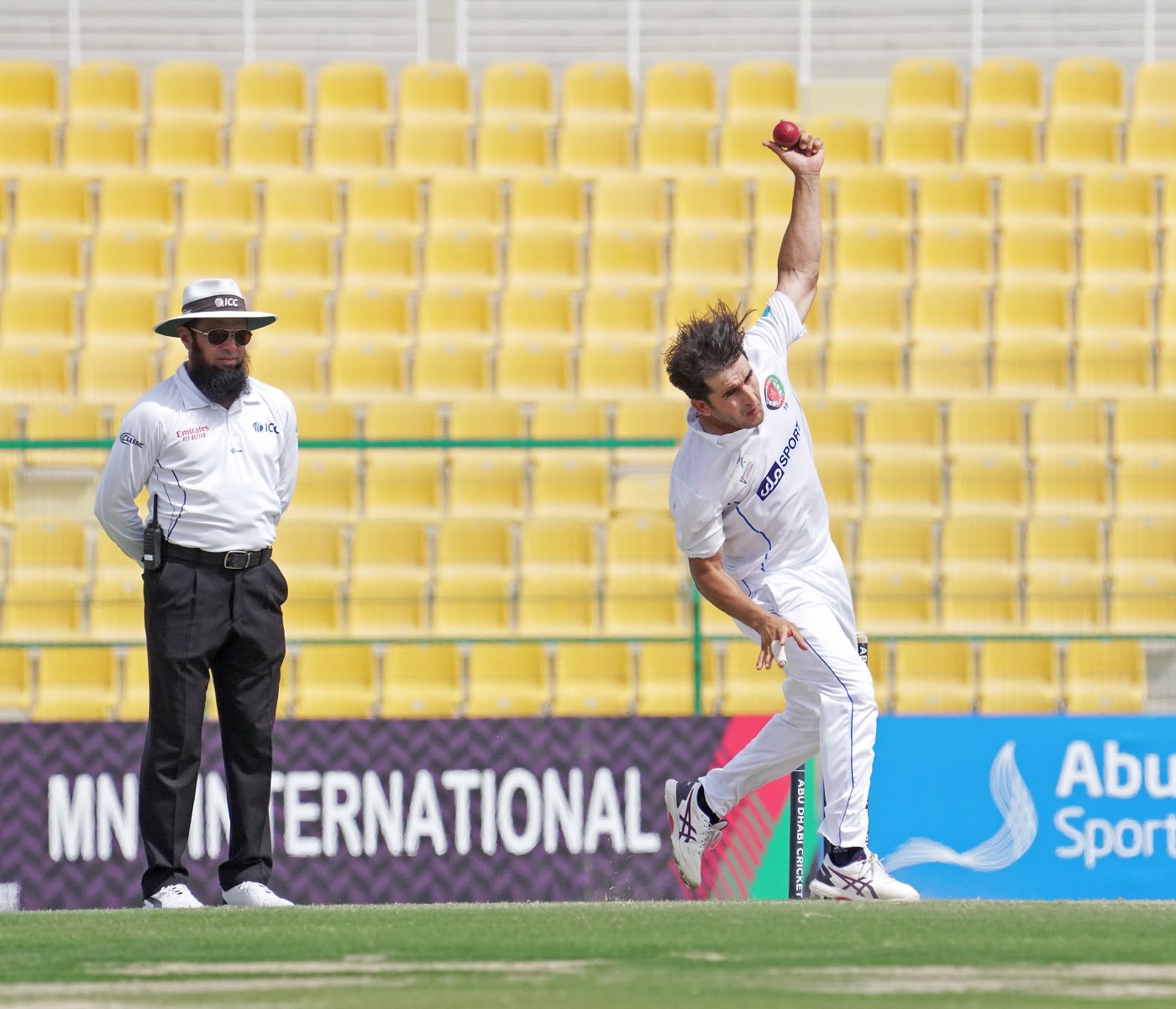 Amir Hamza bowls as umpire Aleem Dar looks on