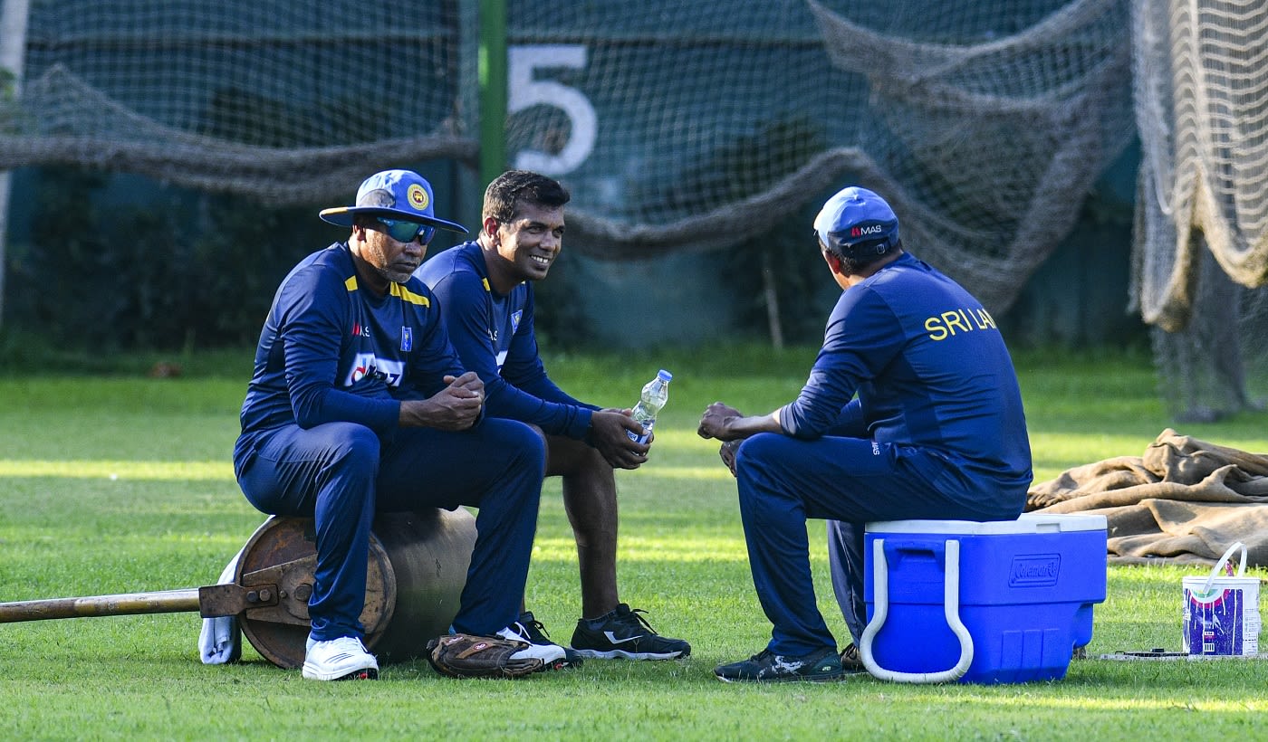 Chaminda Vaas (L) takes a break during a training session