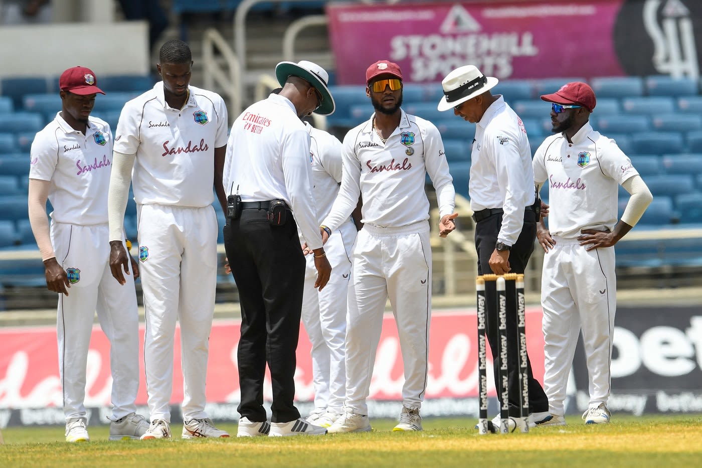 Kraigg Brathwaite gestures to the umpires about the damp spot that's affecting Jason Holder's run-up