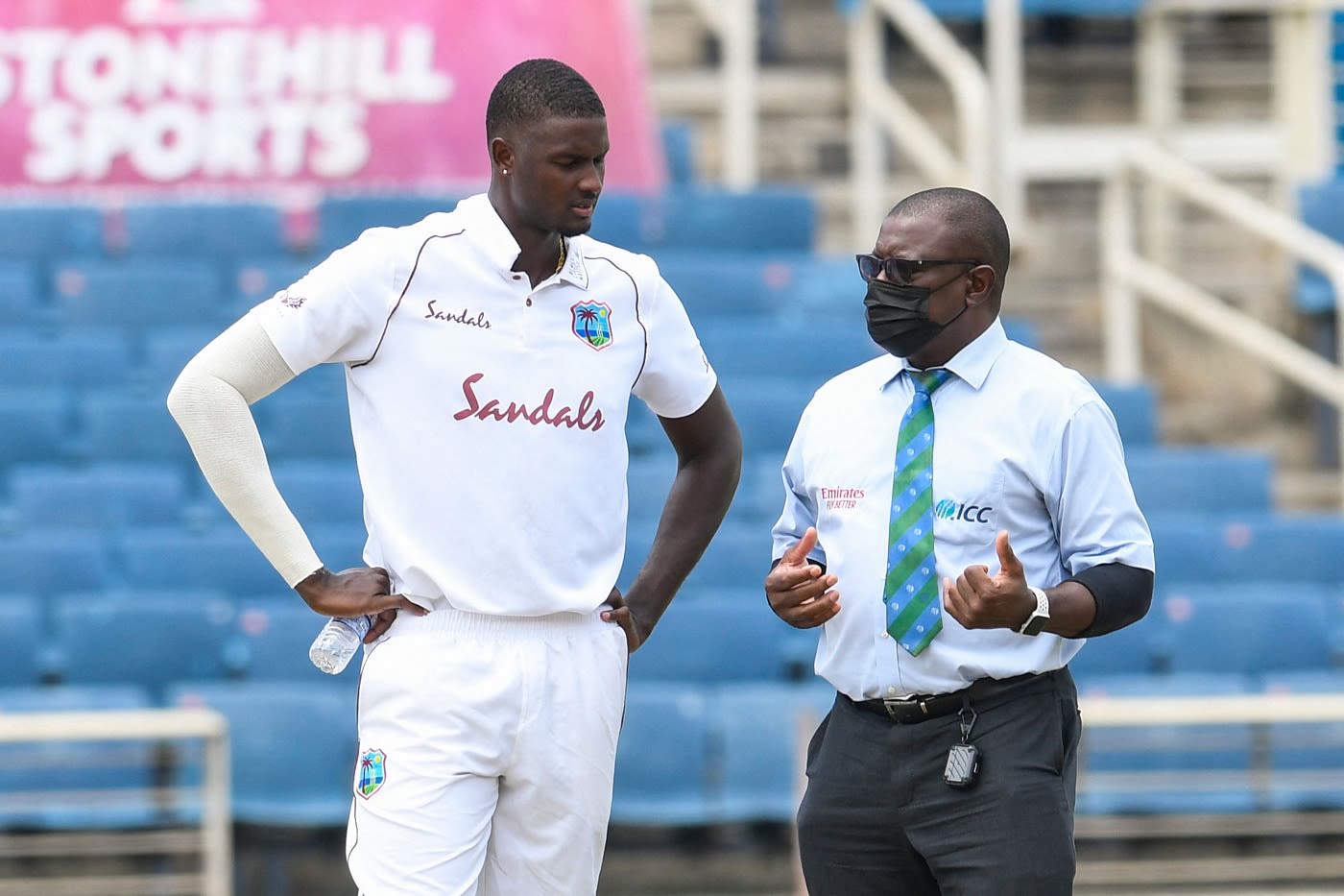 Jason Holder talks to match referree Richie Richardson about the wet spot on his run up
