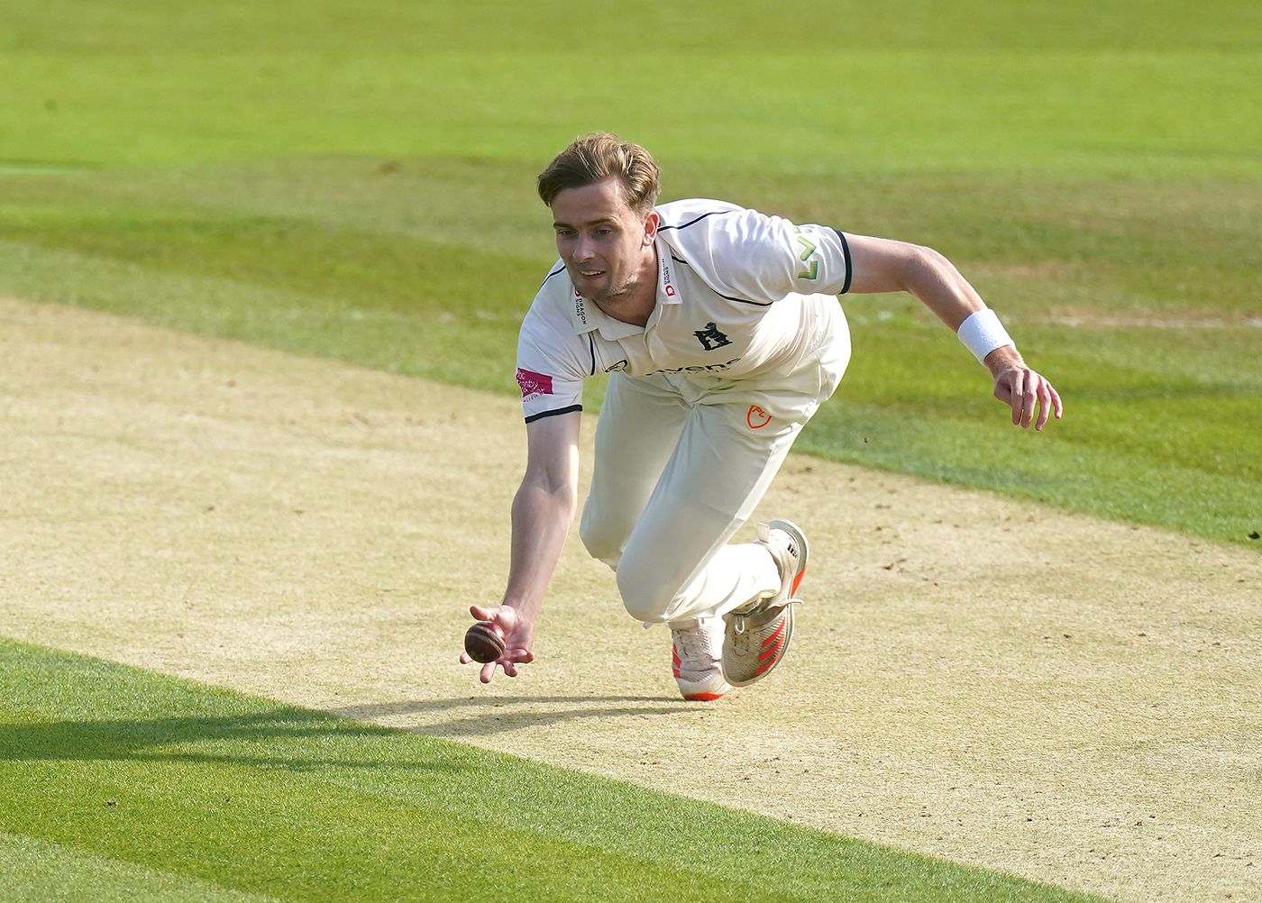 Craig Miles stoops for a low catch off his own bowling