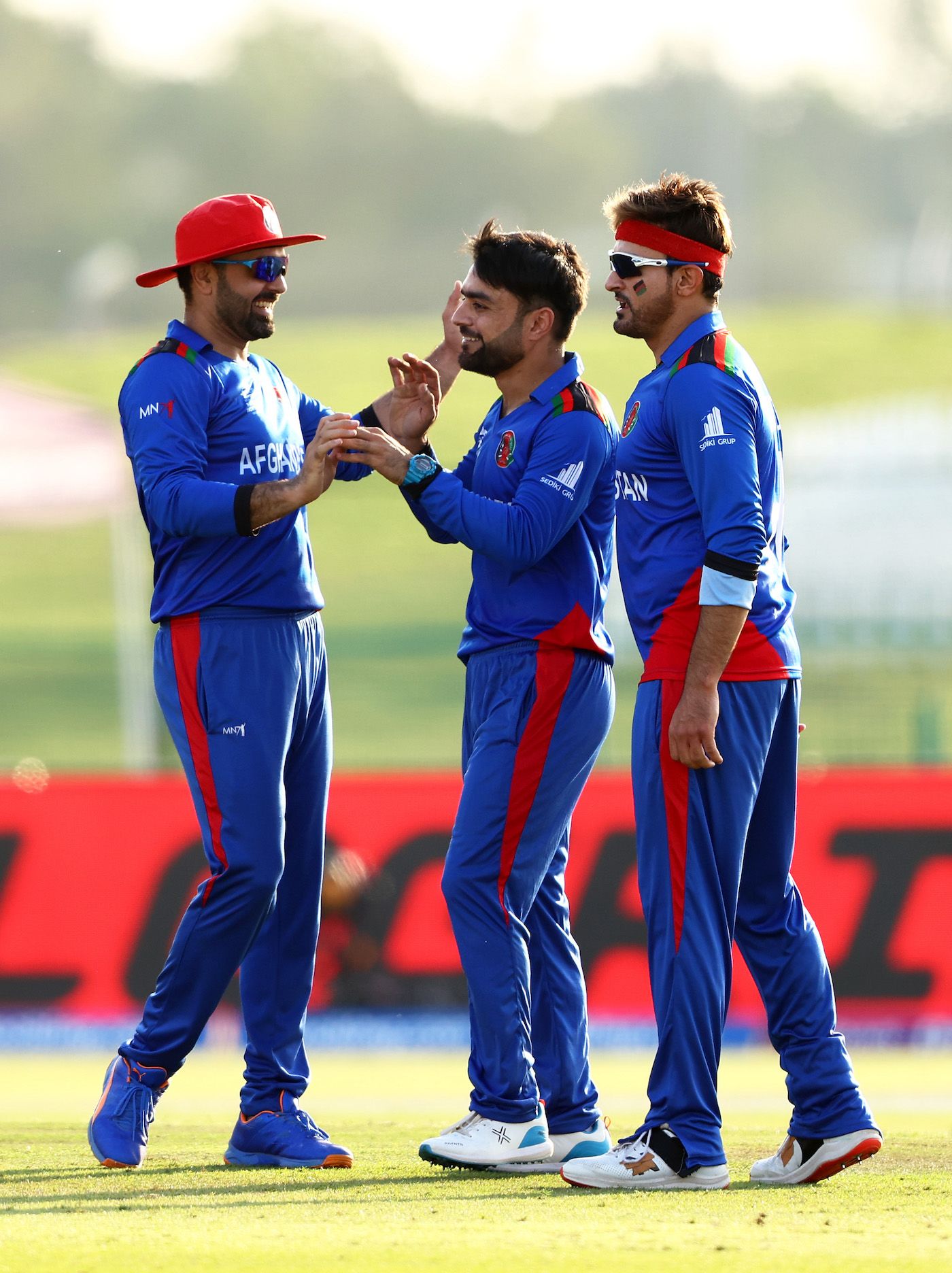 Mohammad Nabi and Hamid Hassan congratulate Rashid Khan after he picked up his 400th T20 wicket