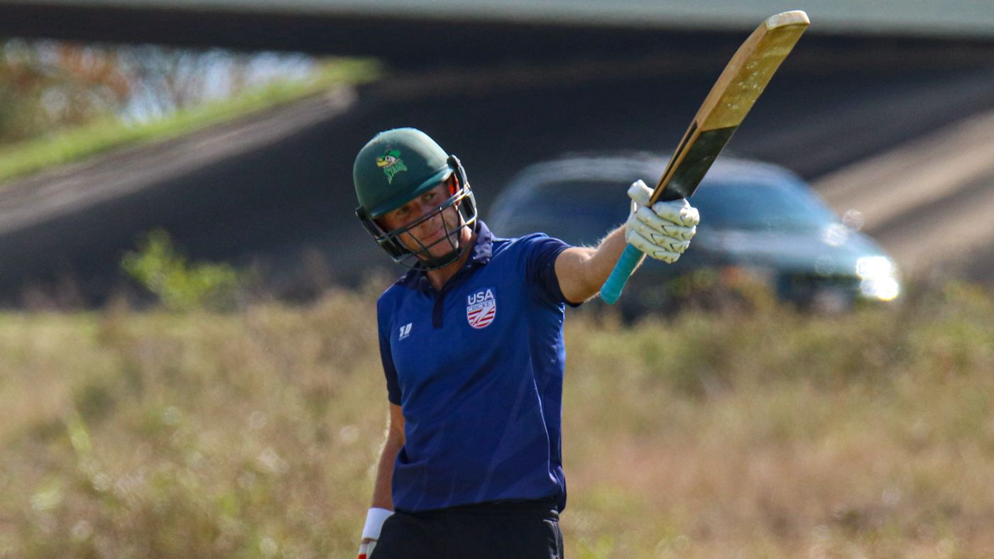 Marty Kain raises his bat after reaching a half-century