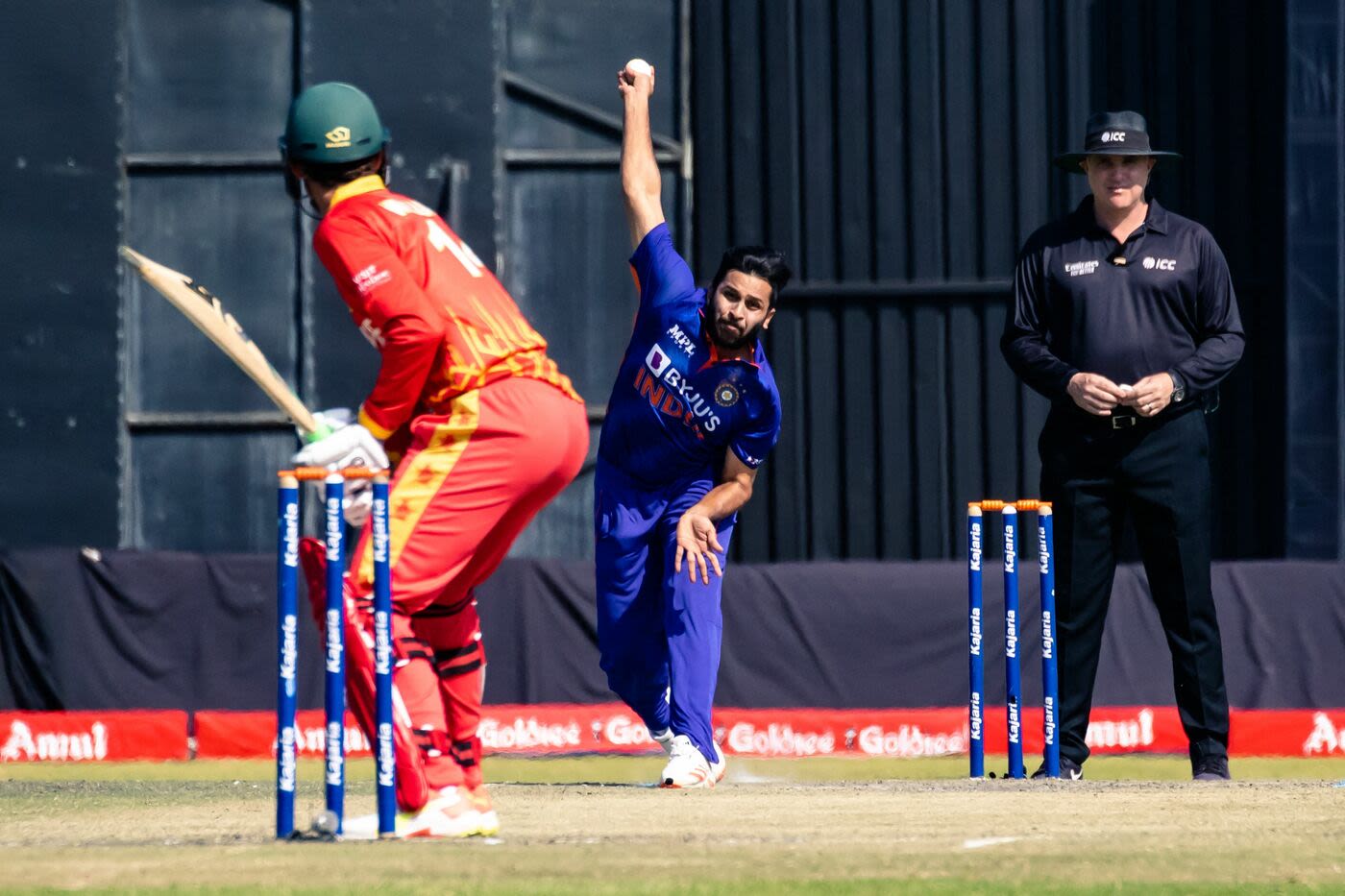 Shardul Thakur bowls to Sean Williams, with umpire Adrian Holdstock overseeing