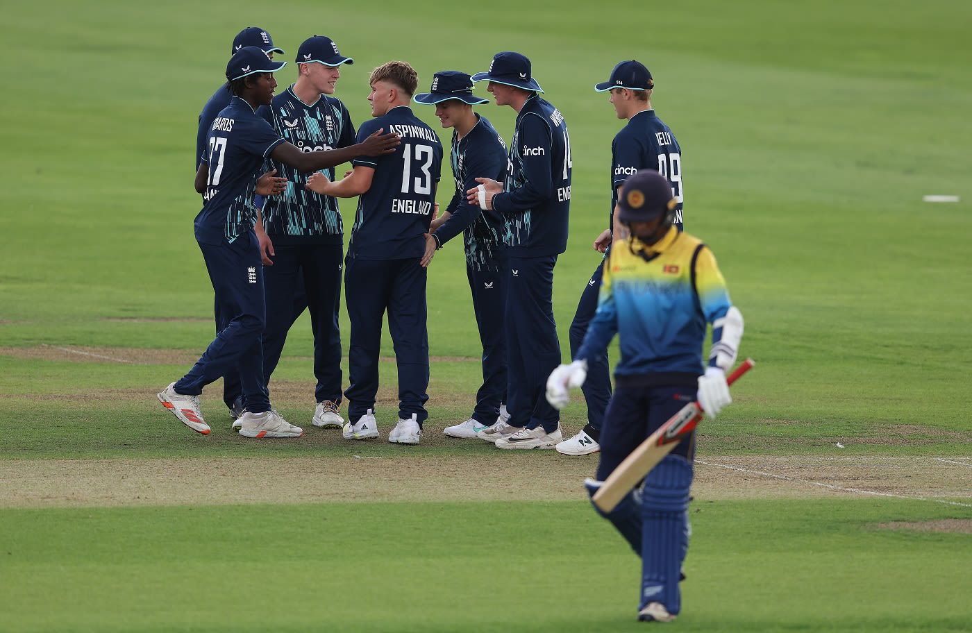 Thomas Aspinwall is congratulated by his team-mates after he dismissed Abisheak Liyanaarachchi