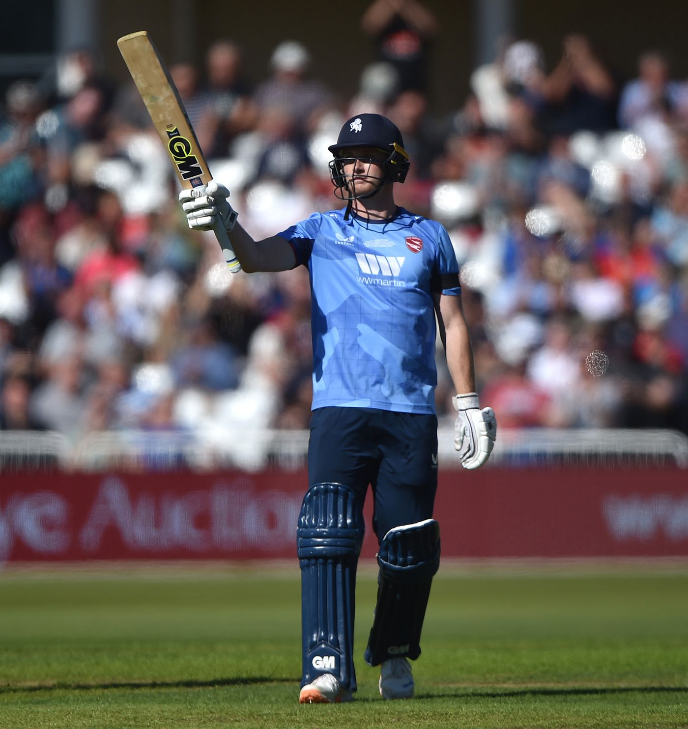 Joey Evison raises his bat after scoring fifty