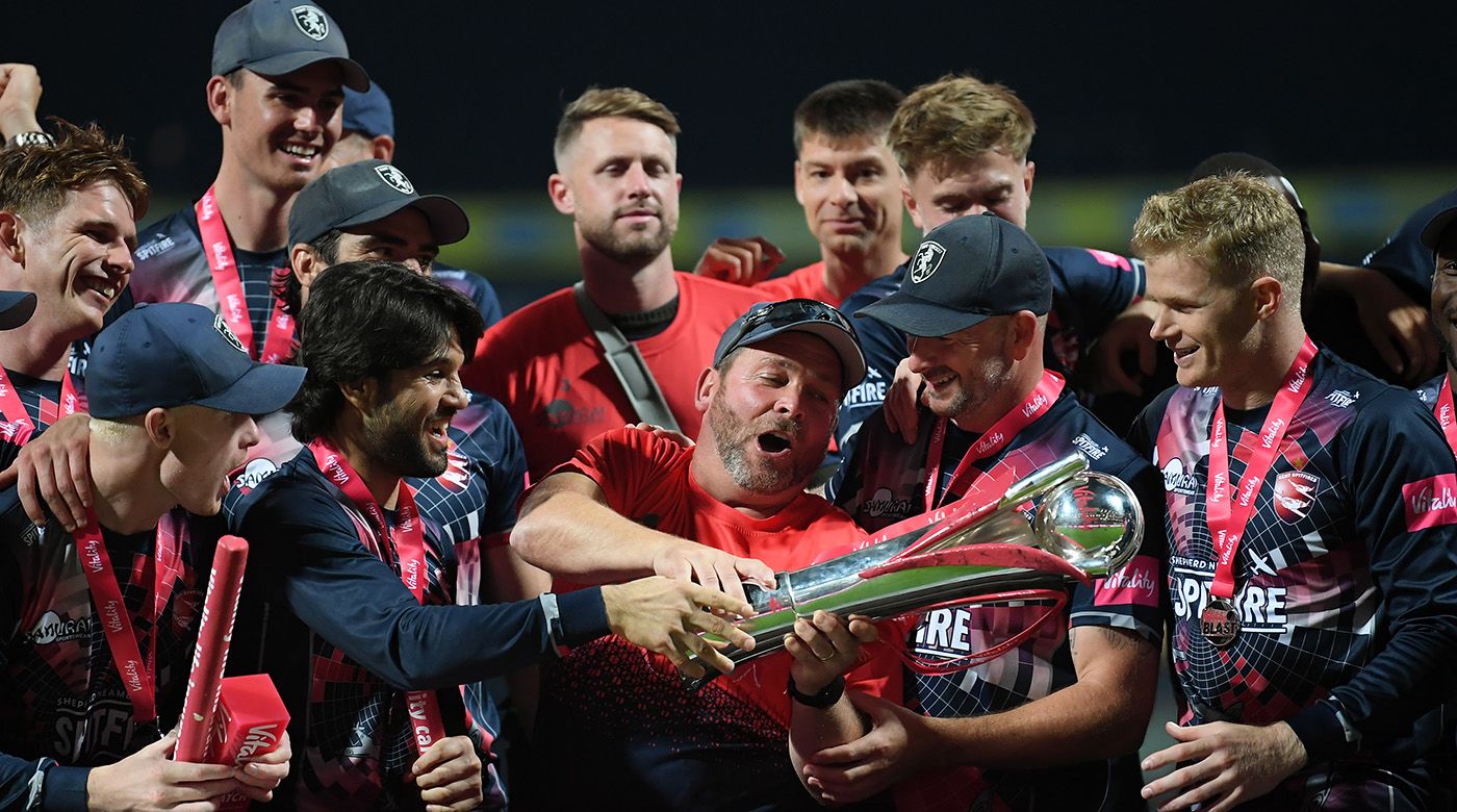Kent captain Sam Billings (right) Darren Stevens (second from right) watch coach Max Walker hold the trophy