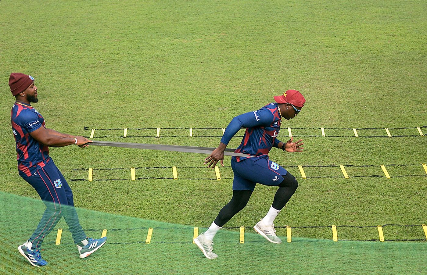 Sunil Ambris helps Rovman Powell train using resistance bands