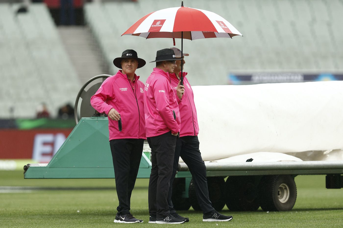 Rain has umpires Paul Reiffel and Adrian Holdstock, along with Paul Wilson, bring out the brollies
