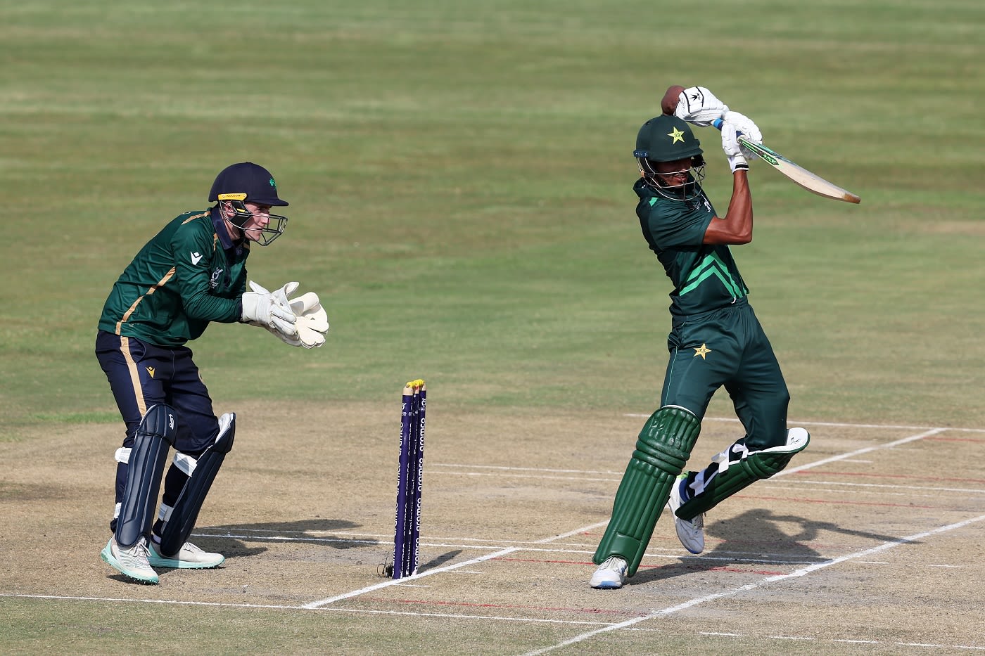 Ahmad Hassan punches one off the back foot as Ryan Hunter looks on