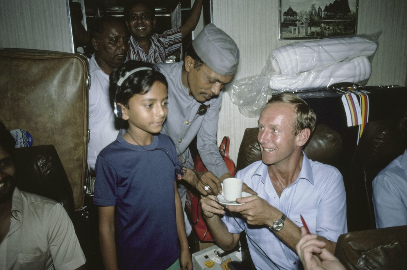 Derek Underwood grabs a cup of tea while a boy listens to his Walkman on the train to Pune