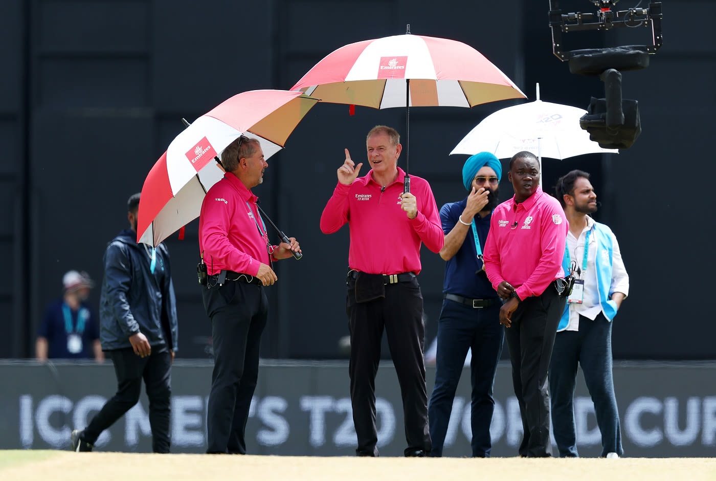 Umpires Paul Reiffel and Richard Illingworth protect themselves from the rain in Tarouba