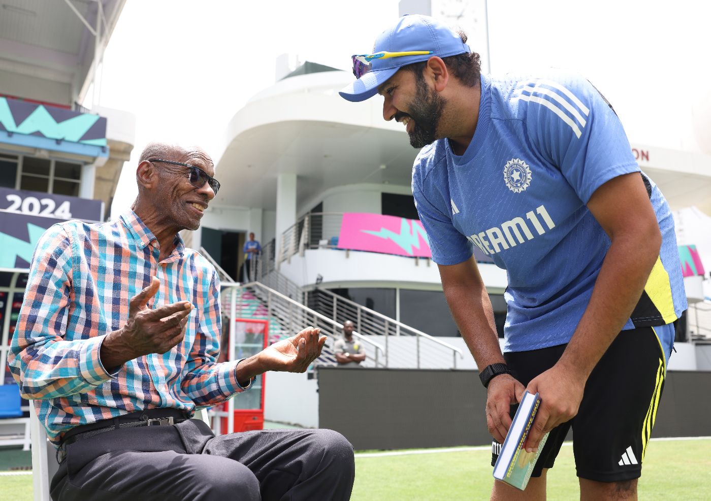 Wes Hall has a laugh with Rohit Sharma while presenting him with his book