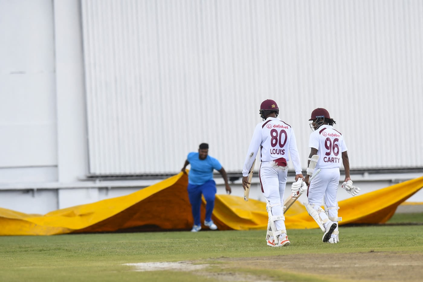 Mikyle Louis and Keacy Carty walk off the field as rain arrives