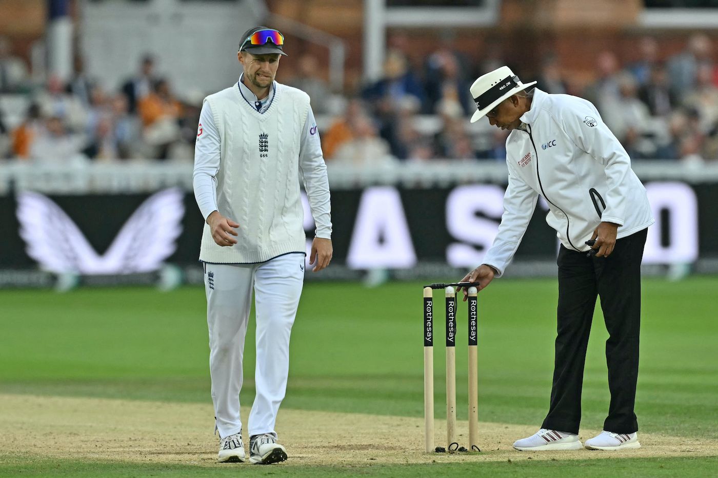 Joe Root passes by as Joel Wilson puts the light meter to work
