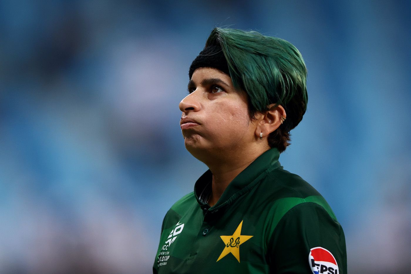 A green-haired Nida Dar looks on