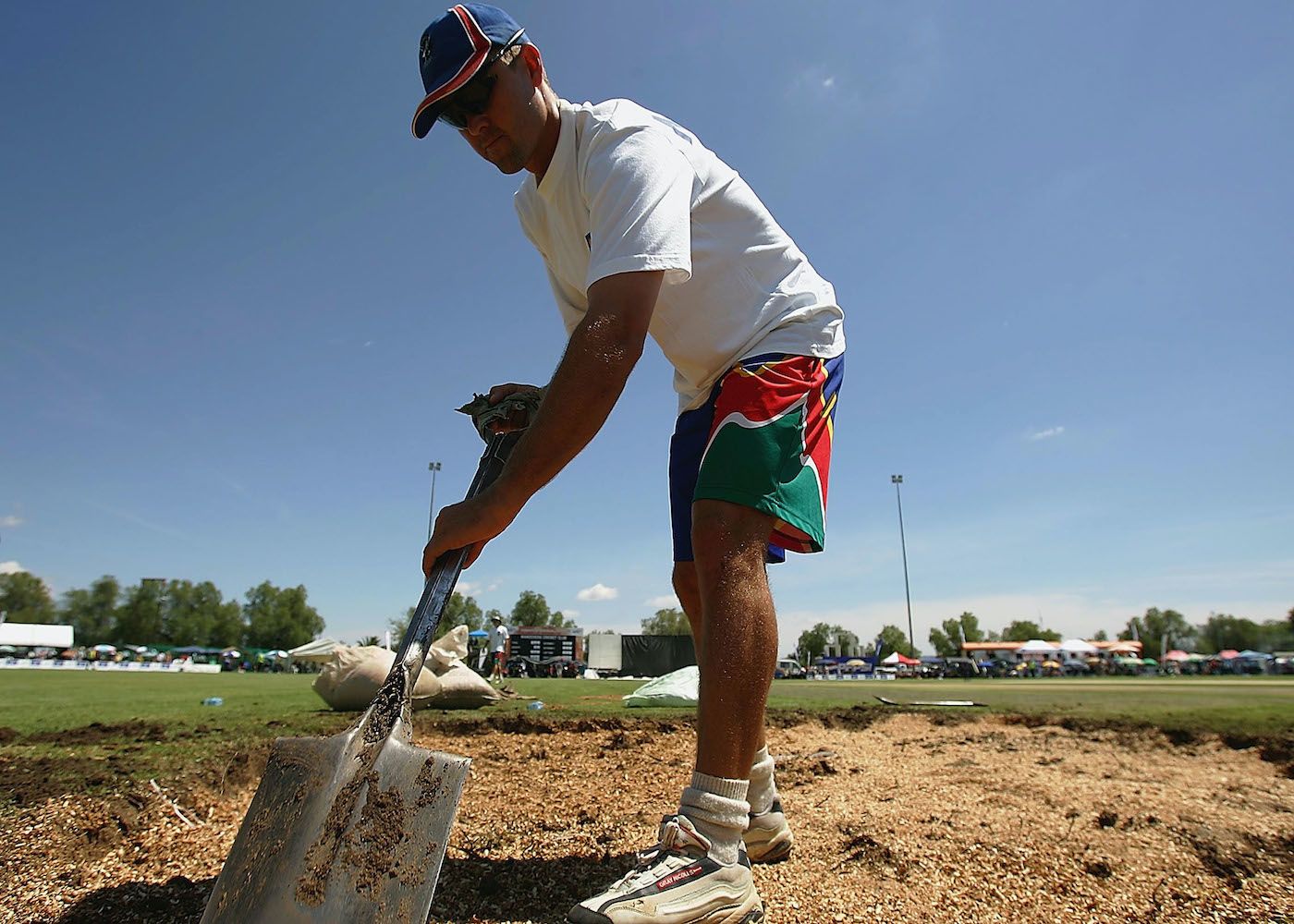 Deon Kotze, the captain of Namibia, helps with drying out the pitch before the start of the match