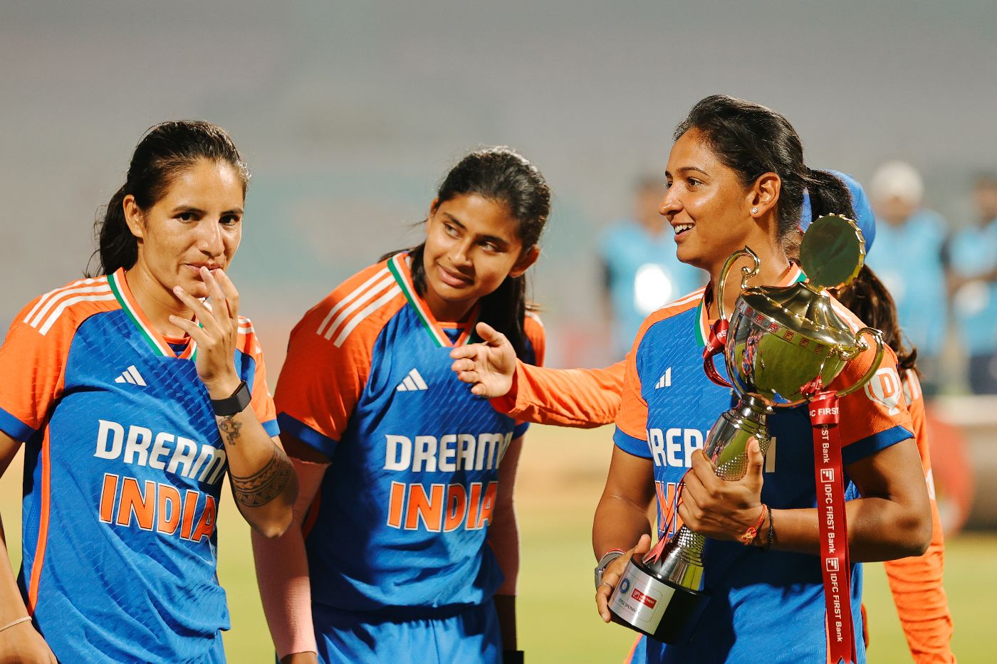 Harmanpreet Kaur collects the trophy as Renuka Singh and Titas Sadhu wait for celebrations to begin
