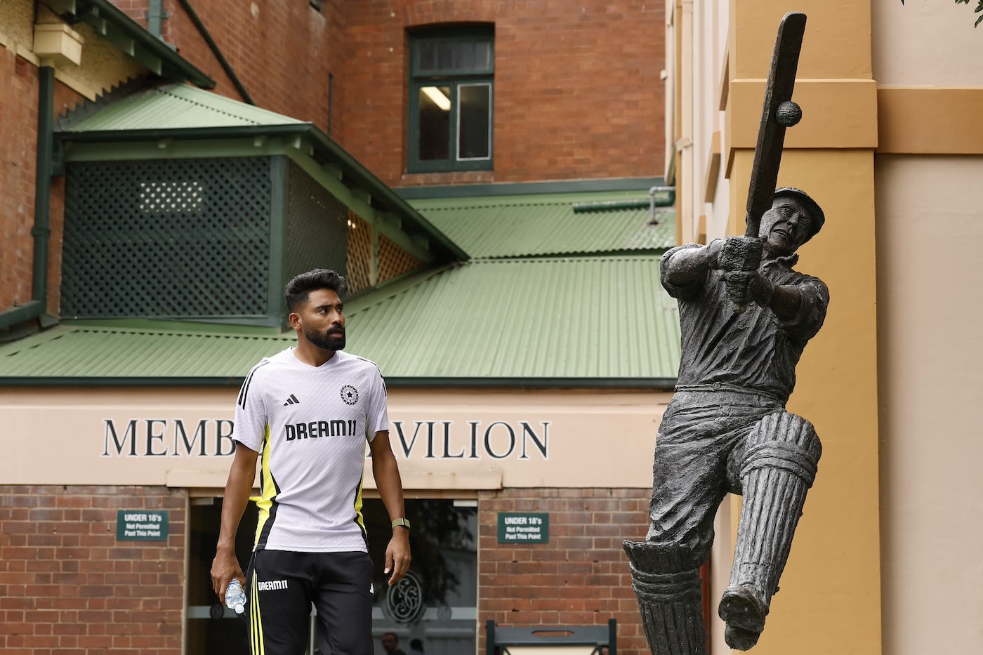 Mohammed Siraj gives the statue of Stan McCabe a quizzical look as he walks past it