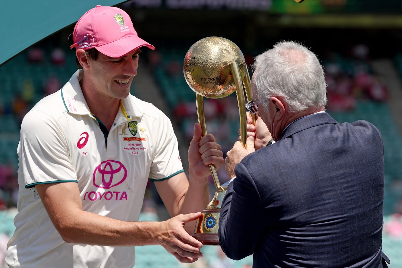 Pat Cummins collects the trophy from Allan Border