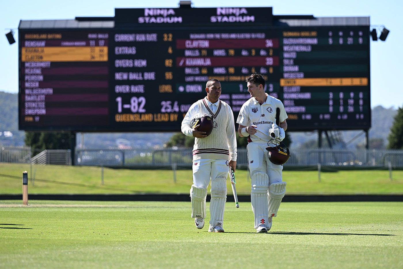 Usman Khawaja and Jack Clayton walk off after completing victory