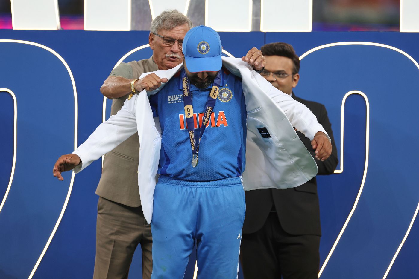BCCI president Roger Binny hands India captain Rohit Sharma his winner's jacket as ICC chair Jay Shah looks on