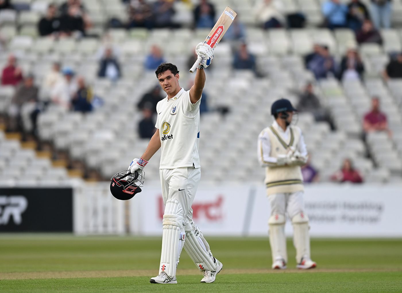 Tom Clark raises his bat on reaching a century