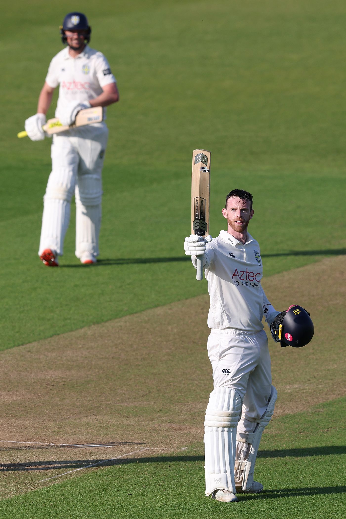 Graham Clark raises his bat on reaching a century