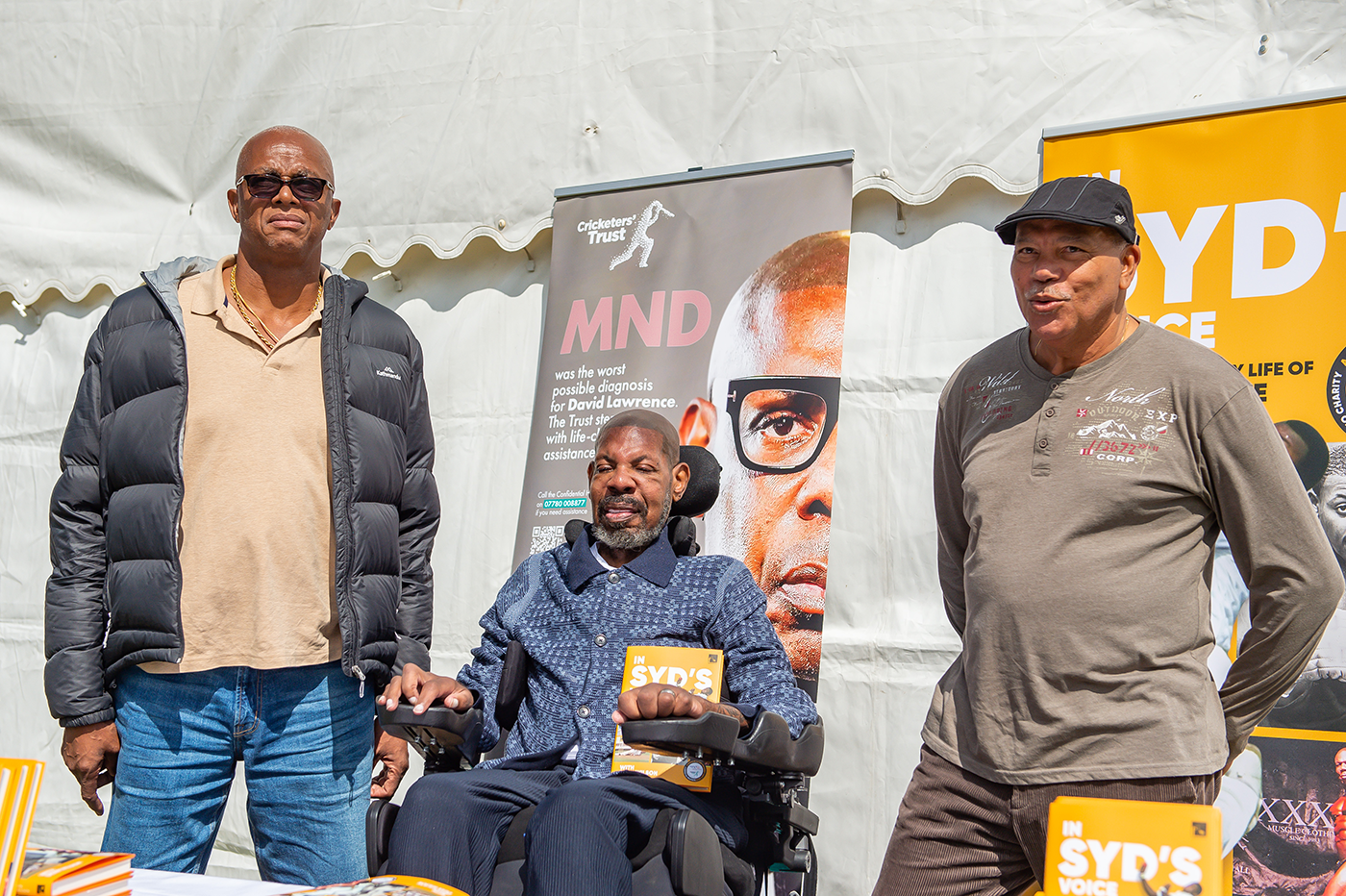 Courtney Walsh and David Lawrence (centre) pose with Lawrence's book <i>In Syd's Voice</i> at a charity event in Downend Cricket Club in Bristol
