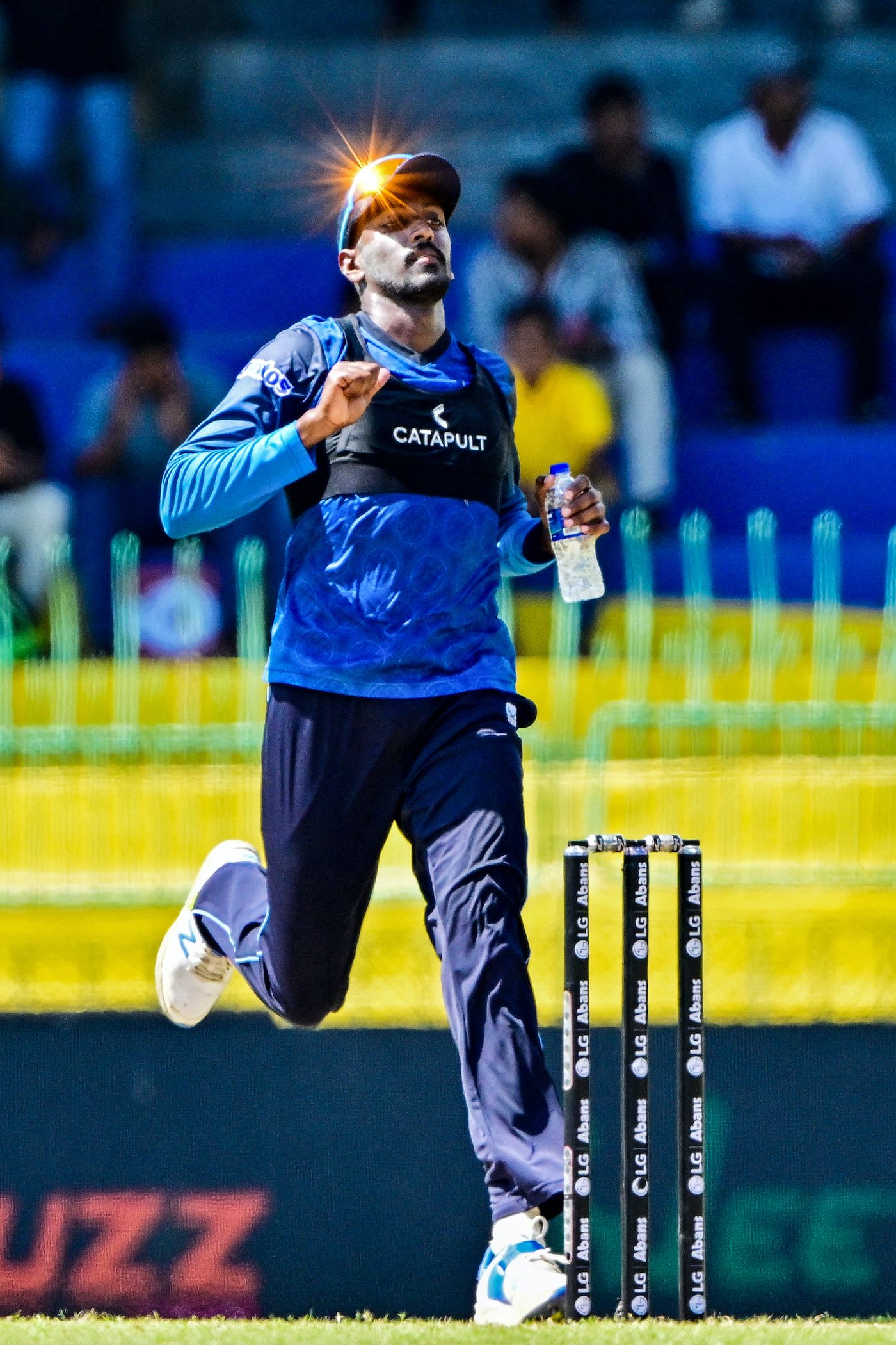 The light catches Milan Rathnayake as he runs on the field