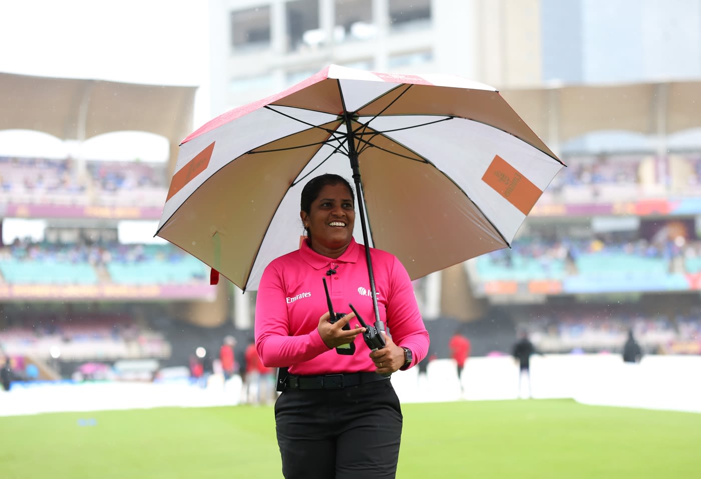 Fourth umpire Nimali Perera in the middle with an umbrella