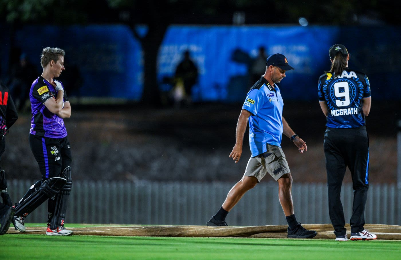 Elyse Villani and Tahlia McGrath inspect the pitch with groundsman Trent Kelly 