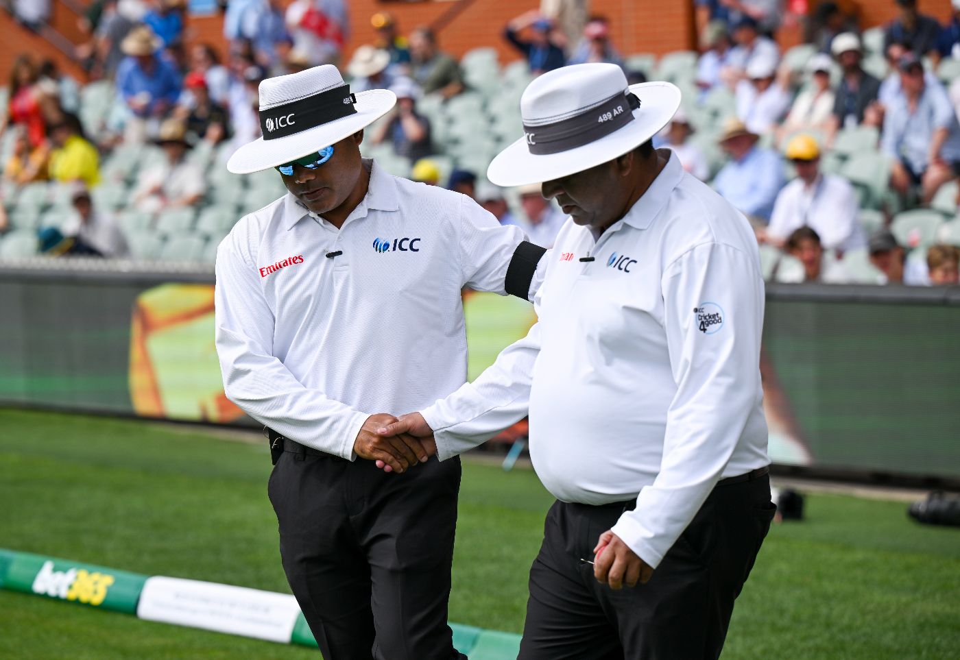 Umpires Nitin Menon and Ahsan Raza shake hands as they take the field